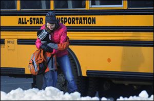 A woman hugs a child before he boards a bus on the first day of classes after the holiday break, in Newtown, Conn. Children from Sandy Hook Elementary School returned to school in the neighboring town of Monroe.