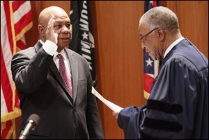 Phil Copeland, left, is sworn in today as Lucas County recorder by Toledo Municipal Court Judge C. Allen McConnell at One Government Center.