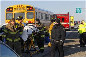 Firefighters and paramedics remove an unidentified woman from a vehicle for transport to St. Luke's Hospital after a car struck a Perrysburg school bus from behind on Dixie Highway near the I-475 overpass. Perrysburg fire department deputy chief Wade Johnson said only minor injuries were reported and no children were injured.