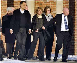 Former U.S. Rep. Gabrielle Giffords, center, holds hands with her husband, Mark Kelly, while exiting Town Hall at Fairfield Hills Campus today in Newtown, Conn. 