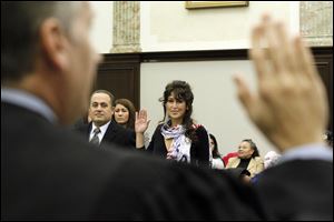 Tia Weber, from Georgia, center, is sworn in by Judge Jeffrey J. Helmick during the naturalization ceremony in U.S. District Court. At left is Hesham Moris Ibrahim Youssef of Egypt.