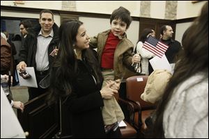 New U.S. citizen Rima Adel Abu-Hamdan of Lebanon holds her son, Adam Abu-Hamdan, 2, while her husband, Maher Abu-Hamdan, follows behind them after the ceremony in District Court.
