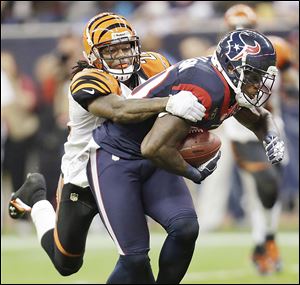 Texans wide receiver Andre Johnson is tackled by Bengals cornerback Adam Jones in the third quarter of Saturday’s AFC wild-card playoff game. Houston advances to play at New England.