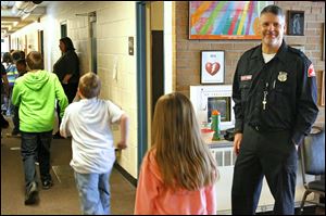 Guard Jerry Lemanski greets children heading for their classrooms at Custer Elementary School in Monroe. ‘I think for par­ents, staff, and kids, it gives them peace of mind,’ Mr. Le­man­ski said.