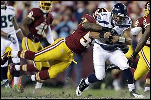 The Seahawks' Russell Wilson drags the Redskins' London Fletcher during a play in the first half. Washington faltered down the stretch as the rookie Wilson led Seattle to a playoff win.