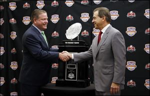 Alabama coach Nick Saban, left, and Notre Dame head coach Brian Kelly pose with The Coaches' Trophy during a news conference for the BCS championship game Sunday in Miami.