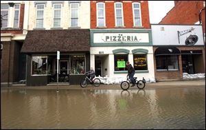 Children ride their bikes through flooded Main Street in Ottawa, Ohio, in 2009, one of several occurrences of the Blanchard overflowing into the town.
