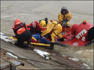 Firefighters pull a woman from a Washington Township fire department boat onto the docks along the Maumee River near Imagination Station after rescuing her from the ice.