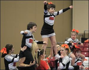 Held up by their Sparks teammates are, from left,  Alvin Gibson, Izzie Vandyke, and Kayliegh Long, all of Toledo, at the Greater Midwest Cheer and Dance Expo at SeaGate Convention Centre on Sunday. The Sparks team, like all the competitors, performed in front of 2,000 spectators.