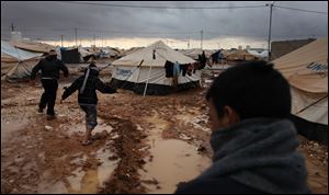 Syrian refugees make their way on water and mud, at Zaatari Syrian refugee camp, near the Syrian border in Mafraq, Jordan, Tuesday, Jan. 8, 2013. Syrian refugees in a Jordanian camp attacked aid workers with sticks and stones on Tuesday, frustrated after cold, howling winds swept away their tents and torrential rains flooded muddy streets overnight. Police said seven aid workers were injured. (AP Photo/Mohammad Hannon)