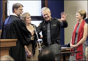 Lucas County Judge Dean Mandros, left, and Phyllis Tharp smile after Maj. John Tharp, becomes the county’s newest sheriff. The Tharps’ daughter, Kati, right, looks on. An overflow crowd was on hand for Monday’s ceremony at the Lucas County Courthouse.