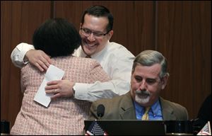 Councilwoman Paula Hicks-Hudson hugs Shaun Enright after he was appointed as the new member of Toledo City Council during a vote at Council Chambers at Government Center in Toledo. At right is councilman Steven C. Steel.