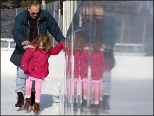 Chuck McKeown of Toledo helps steady his granddaughter, Addison McKeown, 5, as she takes to the ice for the first time at the Ottawa Park skating rink Monday.