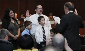 Shaun Enright, center, is sworn in by clerk of council Gerald Dendinger, right,  as the new member of Toledo City Council during a vote at Council Chambers Tuesday. Enright's family is wife Angela, left, and sons from left Michael, 8, Andrew, 11, and Nick, 6, were with him.