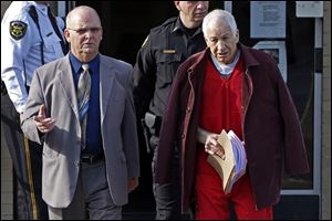 Former Penn State University assistant football coach Jerry Sandusky, left, is essorted by Centre County Sheriff Denny Nau, left, as he leaves the Centre County Courthouse after attending a post-sentence motion hearing in Bellefonte, Pa.