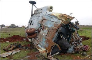 This citizen journalism image provided by Edlib News Network, ENN, which has been authenticated based on its contents and other AP reporting, shows a dead Syrian soldier, left, loyal to Syrian president Bashar Assad, on the ground next to a destroyed helicopter at Taftanaz air base.