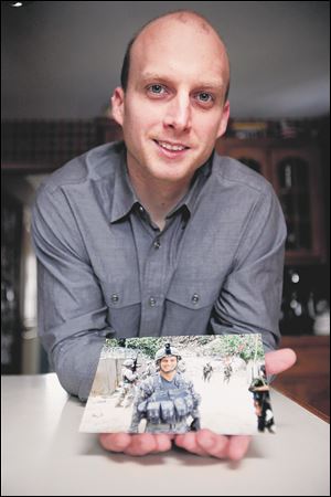 Kyle Tucker, of Sylvania, poses with a picture of himself during his 2008 deployment to Afghanistan.