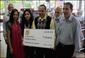 Urooj Khan, center, holding a ceremonial check in Chicago for $1 million as winner of an Illinois instant lottery game. At left, is Khan's wife, Shabana Ansari. Khan, 46.