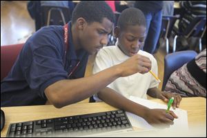 Husani Webb, 16, a junior at East English Village Prep Academy, left, tutors Louis McMillan, 12, a seventh-grader at Clark Elementary School in Detroit. Lear Corporation has created a tutoring program at 2 DPS schools that goes so much farther. The company donated a semi-truck full of furniture, fixed the school's air conditioning, bought every teacher a computer, bought a new computer lab worth of computers and  paid for tutor training that is being provided by the high school students who are getting paid to tutor younger students.