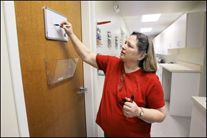 Dr. Kittsen McCumber stands in the hallway area and writes on a white board in the examining room area of the new Animal Emergency and Critical Care Center of Toledo building on Douglas Rd.