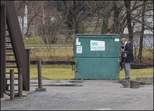 Toledo police Det. Robert Schroeder peers into a Dumpster behind the apartment where Joan Annette Watson's body was found. An autopsy is scheduled for today.