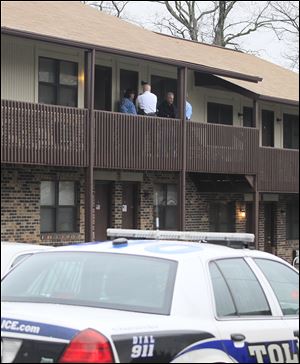 Police officers wait for a crime-scene investigator outside the apartment building on Sylvania Avenue in West Toledo where Joan Annette Watson’s body was found Sunday morning.