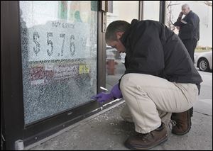 TPD's Terry Cousino digs for the bullet that lodged into the door at the Madison Market/Le Pam Pam store in Toledo.
