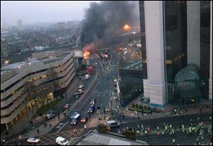 In this overhead view showing smoke and flames at the site of a helicopter crash in central London, as people gather to view the scene shortly after the incident.