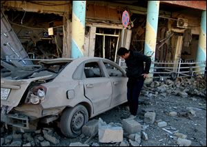 A man inspects his destroyed car at the scene of a bomb attack in Kirkuk, 180 miles north of Baghdad, Iraq