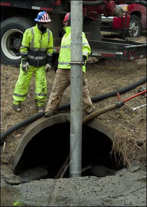 Workers from Pollution Control Services clean oil out of drains affected by the contaminated groundwater under the former Marathon Petroleum Co. refinery on Wednesday, Jan.  16, 2013.  Workers are cleaning up oil and installing screens in the drains to keep oil out.  (AP Photo/The Muskegon Chronicle, Ariana van den Akker) ALL LOCAL TV OUT; LOCAL TV INTERNET OUT