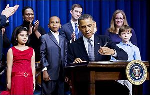 President Barack Obama, accompanied by children who wrote to him about gun violence, signs executive orders aimed at reducing violence.