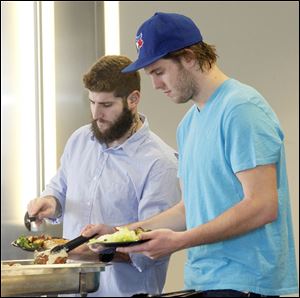 Hockey players Cody Lampl, left, and Ben Woodley, right, help themselves to fried walleye at a luncheon held at the Huntington Center. Some players had never sampled the Lake Erie specialty. 