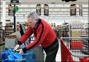 Darrel St. Aubin bags his groceries after shopping in Kirkwood, Missouri. Stores are targeting male shoppers with more man-centric displays and gender-neutral packaging.
