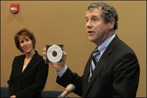 Sen. Sherrod Brown (D-Oh.), right, with a copy of the foreclosure training manual ABLE created for attorneys to use to help clients. At left, rear, is Luckey Mayor Belinda Brooks.