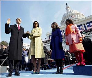 Standing in the rain, President George W. Bush waves as he watches his inaugural parade pass by the White House viewing stand in Washington, Jan. 20, 2001. 