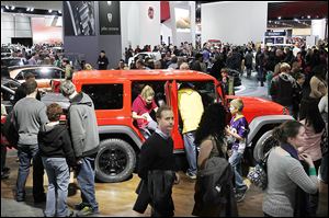 People crawl in and out of a Jeep Wrangler Unlimited Moab edition during opening day of the North American International Auto Show in Detroit. Jeep also had several Wranglers on the show floor.