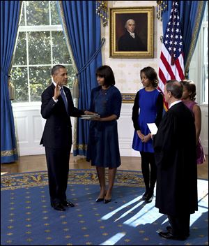 President Obama is sworn in with the family Bible held by First Lady Michelle Obama, as daughters Malia and Sasha watch in the Blue Room of the White House. Supreme Court Chief Justice John Roberts administered the oath on Sunday.