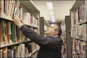 Eric Perron of Toledo, in the Sylvania Branch library, looks for books on basement refinishing.  Patrons of newly reopened library branches are happy to see the  reinstatement of Sunday hours.