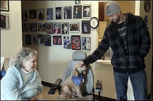 Mobile Meals volunteer Mike Bunker of Erie, Mich., strokes Buddy as he makes a pet  food delivery to Shirley Crye and her dog at Alpha Towers in Toledo on Monday.