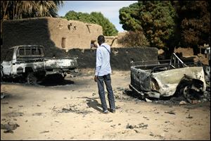 An unidentified man takes a picture of  the charred remains of trucks used by radical Islamists on the outskirt of Diabaly, Mali,  some  460kms (320 miles) North of the capital Bamako, Monday.