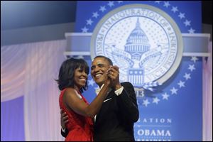 President Barack Obama and first lady Michelle Obama, wearing a ruby colored chiffon and velvet Jason Wu gown, dance.