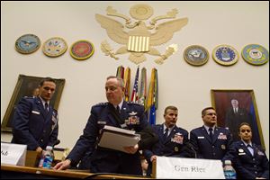 Air Force Chief of Staff Gen. Mark Welsh III, second from left, picks up papers during a break in his testimony today on Capitol Hill in Washington.