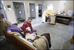 Jane Huth, right, and Anne Schumann, operators of You Lucky Dog, spend time with Max in Oregon. The rescue group faces a $1,500 bill to replace drywall and flooring damaged by flooding.