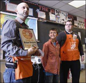 Home Depot’s Keith Young, left, and John Smith give Perrysburg Junior High School student Michael Skotynsky a plaque for writing to the store, requesting assistance for Cherry Street Mission.