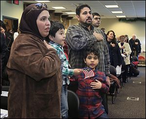 Dalih El-Far, left, her husband, Mohamed, hand on heart, and two of their children, Hashim, 3, and Ahmed, 6, say the Pledge of Allegiance during Thursday's naturalization ceremony. 