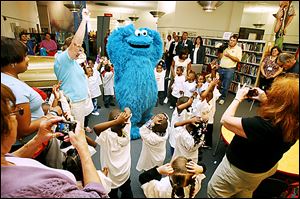 Cookie Monster from ‘Sesame Street’ leads  Toledo Head Start students in a singalong game as parents and teachers snap photos at Toledo-Lucas County Public Library.