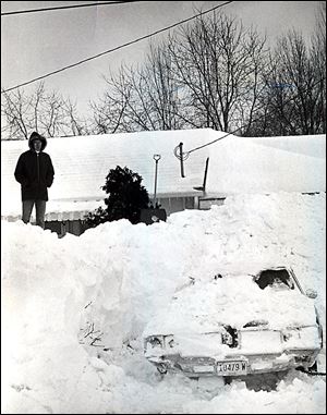 Dave Rickenberg of Liberty Center, Ohio, stands atop a seemingly mountainous snowdrift at his home, where he spent four hours digging out the car in his driveway.