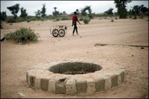 A man pulls a cart past a well where several bodies were dumped in Sevare, north of Mali's capital, Bamako. A witness told The Associated Press that he saw soldiers fatally shoot at least three people at a nearby bus stop and dump their bodies in the well. 