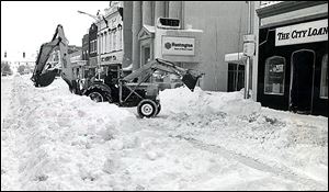 A backhoe operator works at clearing snow on South Main Street in downtown Bowling Green after the blizzard of 1978. Crews stopped only long enough to refuel.