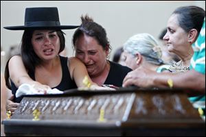 Relatives weep next to a coffin. The bodies of the victims of Sunday's fire were taken to a gym to await identification.